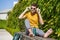 Male sitting outside using an aluminum water bottle, headphones and backpack.