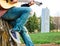 Male sitting on tree stump playing guitar