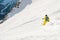 A male skier freerider with a beard descends the backcountry at high speed from the slope