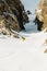 A male skier freerider with a beard descends the backcountry at high speed from the slope