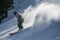 Male skier going downhill on a high speed leaving fresh powder snow behind. Active lifestyle and sport concept.