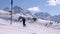 Male skier going up the slopes with skies. Scenic mountain range on a sunny day in Alps.