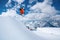 A male skier in an orange suit flies in the air after jumping from a snow sweep high in the Caucasian mountains on a