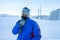 Male skier is standing on a winter street in front of residential buildings on a very frosty day