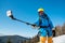 Male skier using selfie stick taking photos while skiing