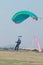 Male skydiver coming in for landing on grass with open green par