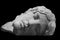 Male sleeping head of old marble roman statue under a black background