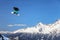 A male snowboard rider flying from a ski jump on snowy mountain background