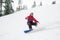 Male snowboarder riding down from the mountain in winter day