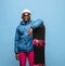 Male snowboarder with snowboard in bright ski suit isolated on blue background