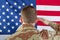 Male soldier saluting large USA Flag while indoors