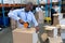 Male staff packing cardboard box with tape gun dispenser in warehouse