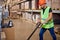 male staff worker in warehouse uses hand pallet stacker to transport goods, alone