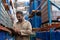 Male staff writing on clipboard while standing in warehouse