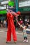 A male stilt walker bends down to shake hands with a little girl