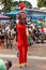 A male stilt walker in bright red clown garb on the street