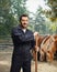 Male stud farm worker in a uniform posing with horses