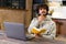 Male student pondering and looking away while writing in a notebook at home. He using laptop to watching a lecture