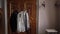 Male suit on a hanger in the bedroom. White shirt, black tuxedo jacket, bow tie.