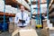 Male supervisor looking at camera while checking stocks in warehouse