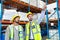 Male supervisor standing with worker and pointing at distance in warehouse