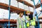 Male supervisor standing with worker and pointing at distance in warehouse