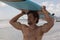 Male surfer carrying surfboard on his head at beach