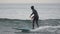 Male surfer in hooded wetsuit rides wave in Pacific Ocean on Kamchatka Peninsula. Slow motion shot