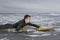 Male Surfer Paddling On Surfboard In Water At Beach