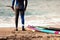 Male surfer wearing a wetsuit standing on the beach sand ready to surf
