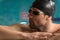 Male swimmer wearing goggles and swimming cap resting