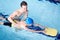 Male Swimming Coach Giving Boy Holding Float One To One Lesson In Pool