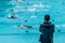 Male swimming coach standing by the swimming pool in the rain wa