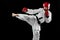 Male taekwondo fighter in white dobok, helmet and gloves training isolated over dark background. Concept of sport