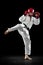 Male taekwondo fighter in white dobok, helmet and gloves training isolated over dark background. Concept of sport