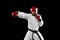 Male taekwondo fighter in white dobok, helmet and gloves training isolated over dark background. Concept of sport