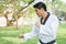 A male taekwondo is standing on green grass and looking ahead in public park