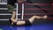 Male tall boxer training with the coach. A sports guy lying on floor on the boxing ring and doing legs exercises with