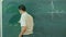 Male teache washes the chalkboard in classroom