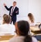 Male teacher lecturing to students at classroom