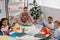 male teacher and multiracial preschoolers sitting at table with colorful papers