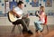 Male Teacher Playing Guitar With Pupil In Classroo