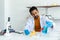 Male teacher in white lab coat with rubber gloves with many lab tools on shelf and table grab the blue reagent bottle on the table