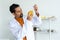 A male teacher in white lab coat using pipette bare hand carefully transfer chemical liquid in yellow flask required