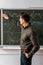 Male teacher wiping mathematical equations with sponge from chalkboard