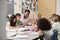 Male teacher works with elementary school kids at their desk