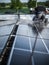 Male team engineers installing stand-alone solar photovoltaic panel system. Electricians mounting blue solar module on roof of