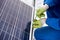 Male technician in blue suit installing photovoltaic blue solar modules with