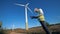 Male technician with a clipboard is observing several windmills. Clean, eco-friendly energy concept.