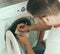 Male technician repairing washing machine.